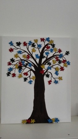 Een boom (levensboom) gemaakt op een schilderij met puzzelstukjes.